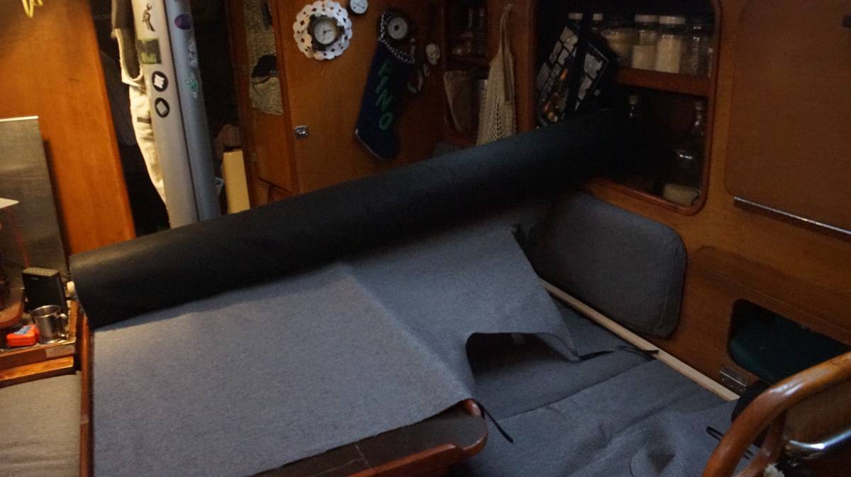 a giant roll of fabric sitting on the tiny saloon table with the right end wedged between jars of dry food