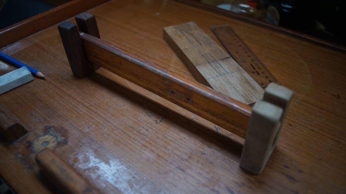 a preview of how the produce baskets will stay in place, showing a horizontal wooden bar sitting between two U shaped blocks