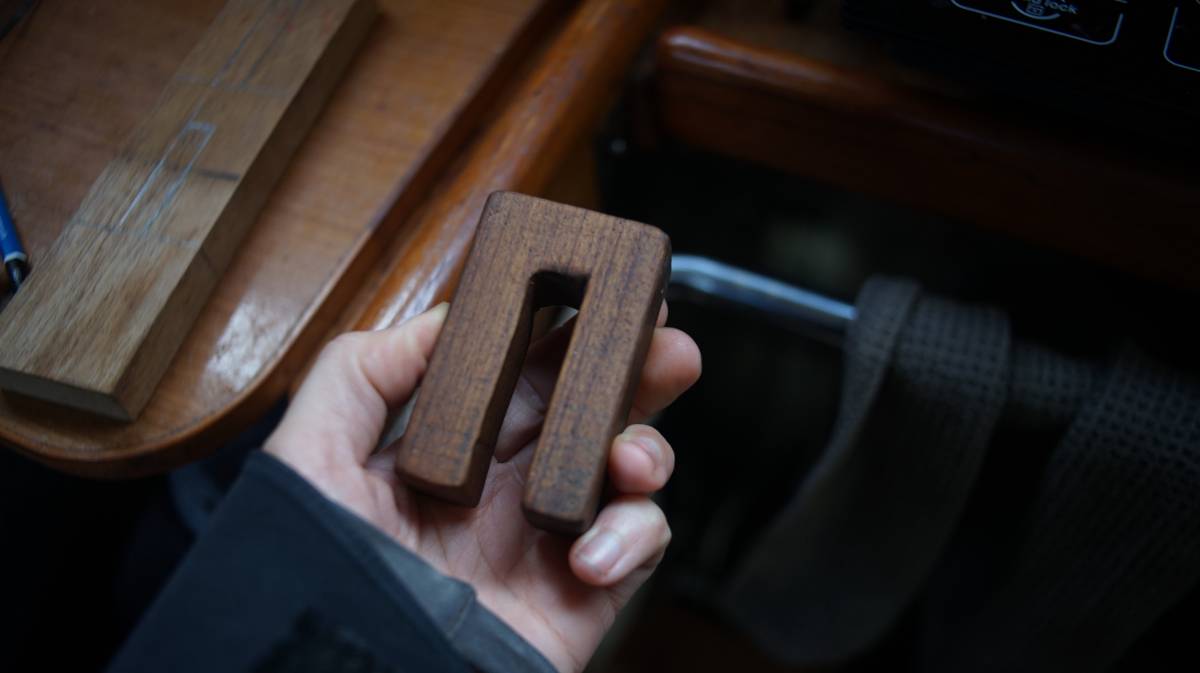 a hand holding a hand carved u-shaped block