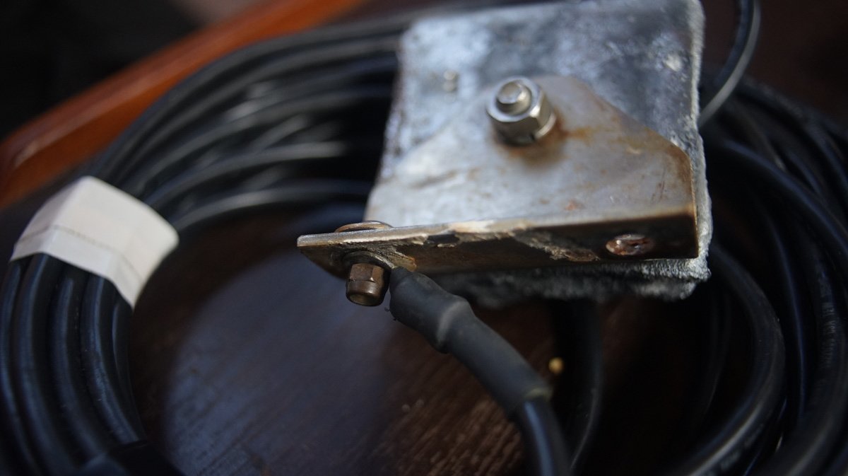 a photo of a piece zinc with a mounting plate bolted into it connected to a long wire