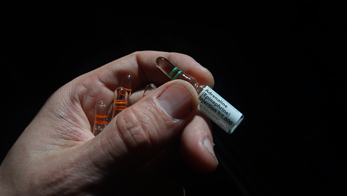 a hand holding an ampule of epinephrine as well as ampules of phenergan