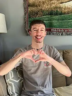 An adult male with Williams syndrome making heart hands.