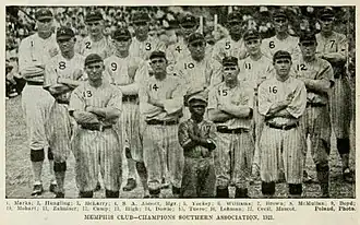 Seventeen baseball players wearing light uniforms with dark vertical pinstripes standing with their arms crossed.