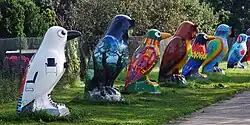 A photo of a line of statues depicting colorful owls and ravens.