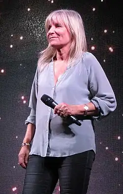 A photo of Ilanit, holding a microphone on stage in 2016