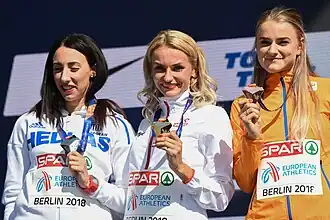 Photo of Maria Belimpasaki, Justyna Święty-Ersetic, and Lisanne de Witte from the waist while wearing track suits and holding their medals