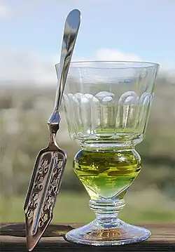Image 4A reservoir glass filled with a naturally colored verte absinthe, next to an absinthe spoon (from List of alcoholic drinks)