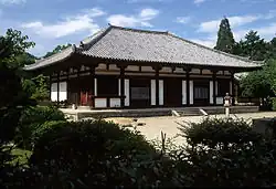 Wooden building on a stone platform with white walls.