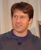 An approximately 38-year-old man looking at something to the left of the camera.