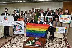 A group of people holding several LGBTQ flags and banners
