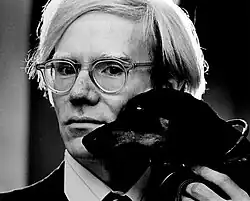 A black and white photo of Andy Warhol with a dog