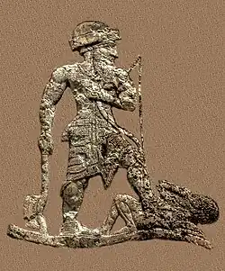 King Anubanini. He is equipped with an axe, a bow and an arrow. He is bare-chested, wears a short skirt, a roll-brimmed hat and sandals.[9][10][1]