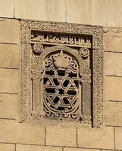 Image of window and lamp carved in stone on the right (reconstructed) side of the façade