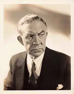 Black and white portrait photo of a white man wearing a suit and tie.