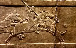 Ashurbanipal on his horse thrusting a spear at a lion’s head.