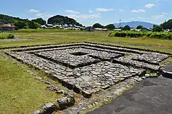 The stone foundations of an ancient building in a grassy environment