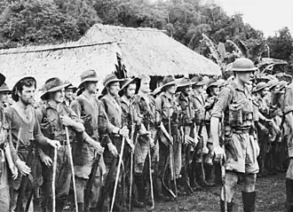 A parade of tired-looking soldiers in a jungle setting