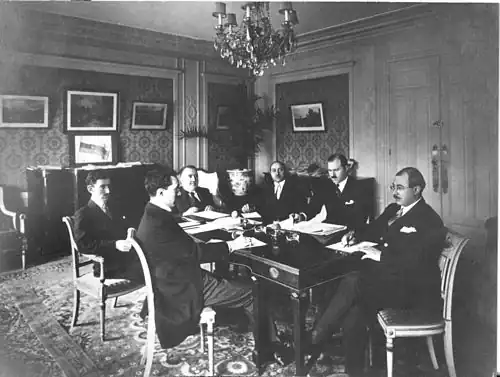 Azerbaijani delegation in Paris at the Claridge Hotel during the Paris Peace Conference, 1919. The tricolour flag of the ADR is visible in the background, on the chest of drawers.