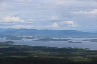 A very large lake with several islands and hills in distance