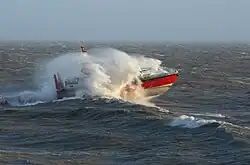 A boat slamming into a wave. There is lots of spray in the air.