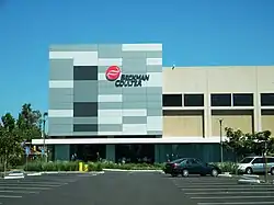 A gray, two-story office building with a parking lot in front