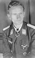 A man wearing a military uniform with an Iron Cross displayed at his neck.