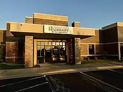 The front of the Nixa branch library is depicted. The library is brick and immediately meets a parking lot.
