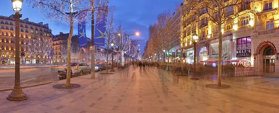 North sidewalk of the Avenue des Champs-Elysées at dawn, featuring Christmas decoration lights.