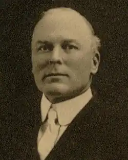 A black-and-white photographic portrait of Harvey from the shoulders up, wearing a suit