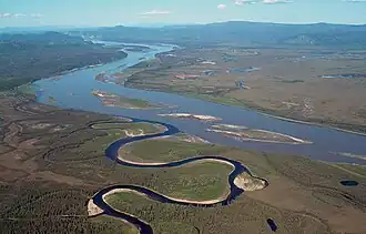 Aerial photo of the narrow horseshoe-bent Charley River flowing into the wide Yukon river with islands in the middle and nearby lakes