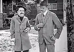 Screenshot of Charlie Chaplin (left) in scene with Henry Lehrman in "Making a Living"