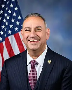 Official House portrait of Cisneros in front of the U.S. flag, wearing a black suit, white shirt, and checkered red tie.