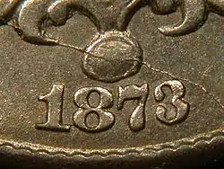 A closeup of part of an 1873 Shield nickel, showing the date, in which the arms of the "3" reach close to each other