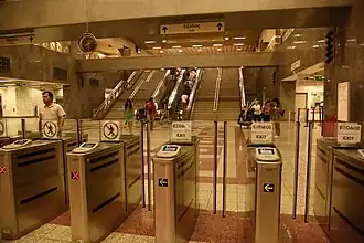 Open indoor area with ticket windows, fare-collection machines and an escalator
