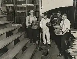 Black-and-white photo of five employees holding damaged books in a basement