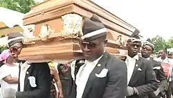 Screenshot of a BBC News video clip showing pallbearers dancing with a casket
