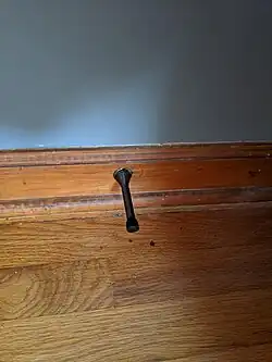 Rigid metal spring doorstop in solid baseboard molding