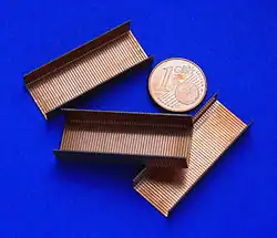 Staple strips used in modern staplers, with a coin for size comparison