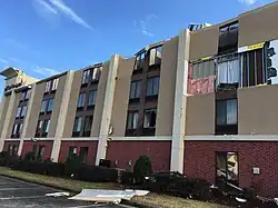 A beige-and-red hotel with broken windows and parts of its exterior missing.