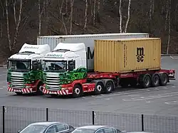 Two large shipping trucks in a parking lot.