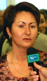 A woman with brown hair, speaking into a microphone.