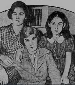 Photograph of two somber-faced young girls on either side of their mother