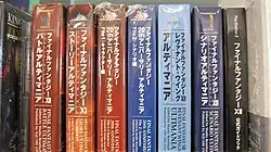 Seven thick large paperback books, each with different Japanese writing on the binding, wrapped in plastic, sitting on a shelf in a row