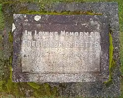 Weathered white marble stone with moss inscribed with Betts's name, birth year, and death year
