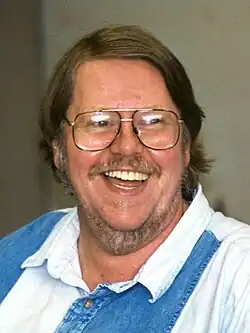 A headshot of a smiling man wearing glasses