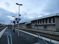 A photograph of an outdoor train platform, the sky above is grey. No trains are visible