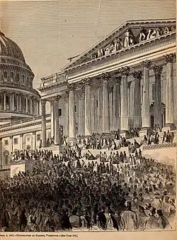 A large crowd in front of a large building with many pillars