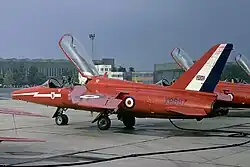 A squadron of one-man jet aircraft, with their canopies open, lined up at a military airbase.