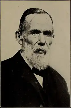 Black-and-white photograph of John Arbuckle, with a white beard and short hair, in a suit with a bow tie.
