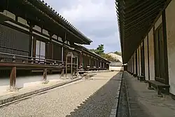 Long wooden building with white walls.